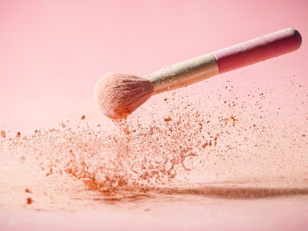 Make up brushes with powder splashes isolated on pink background